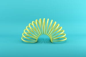 yellow slinky isolated on blue background. minimal conceptual idea concept.