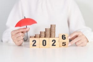 2025 end year to happy new year 2026 with hand holding red umbrella and money stack growing. insurance, protection, safety and new year holiday concepts