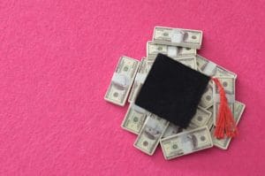 financial investment in higher education: cap and currency on pink